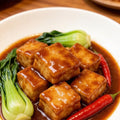 Braised golden fish tofu cubes with bok choy in a clay dish